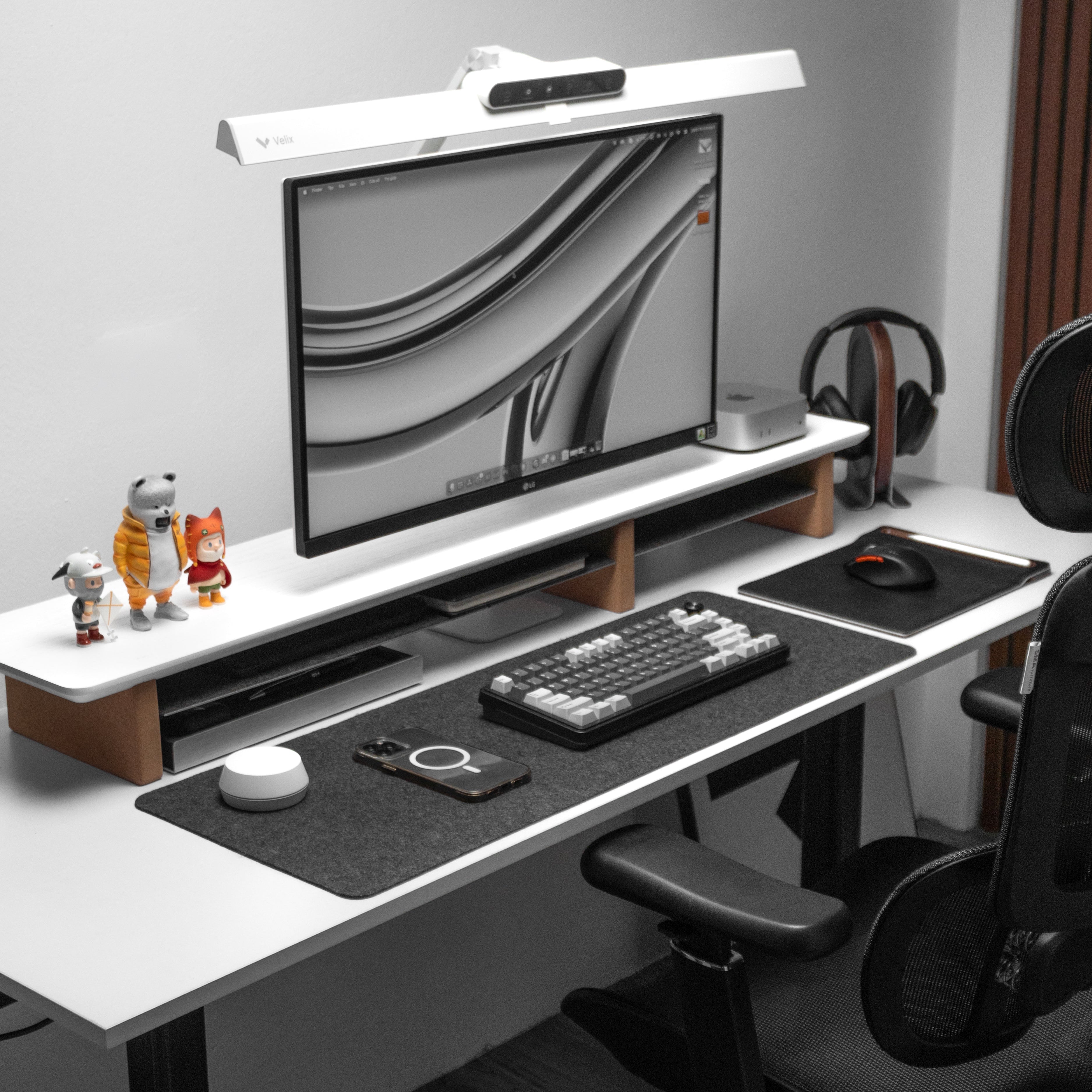 Minimalist home office desk setup with monitor, keyboard, phone, mouse, and desk toys