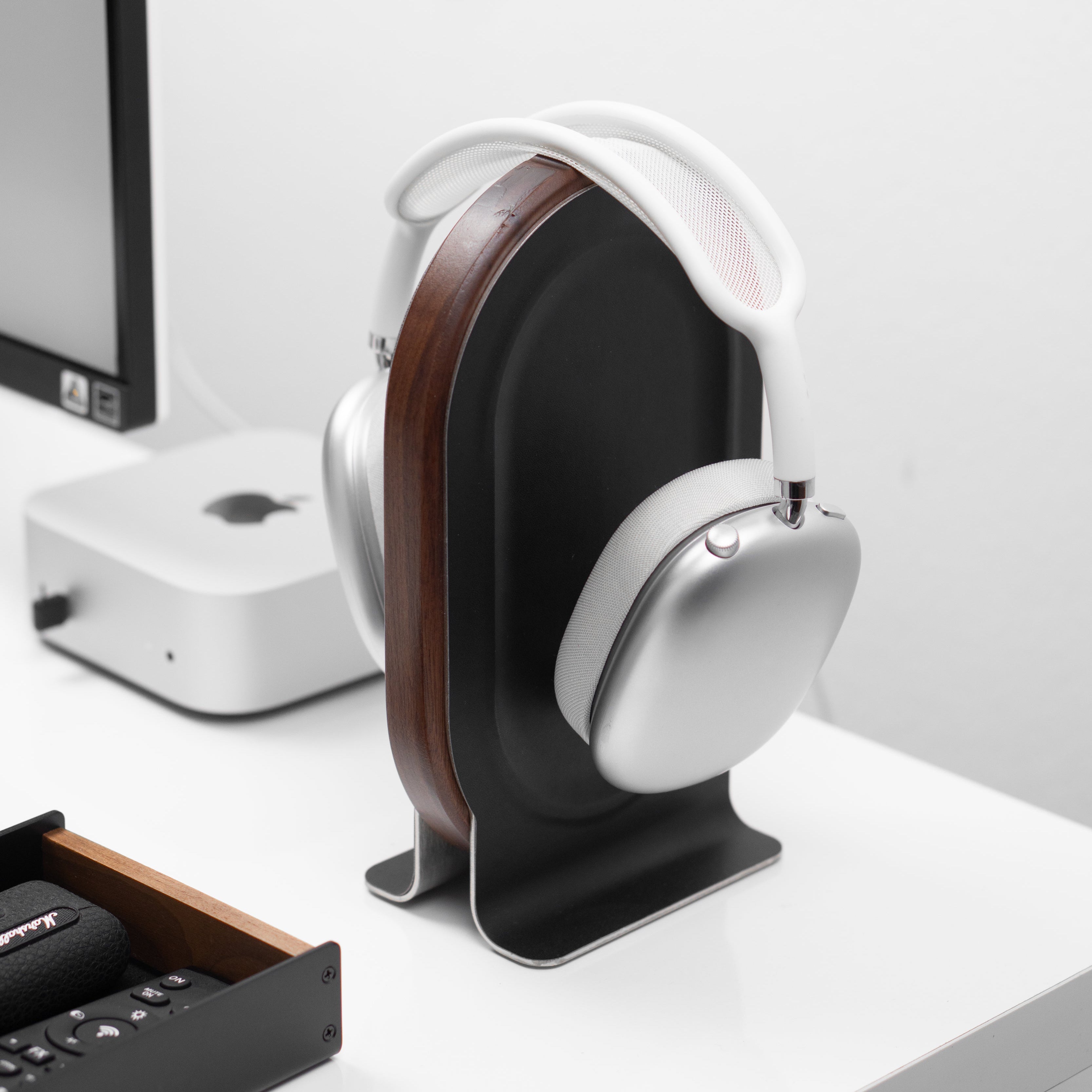 White headphones on a stand in an office setting with a computer and desk.